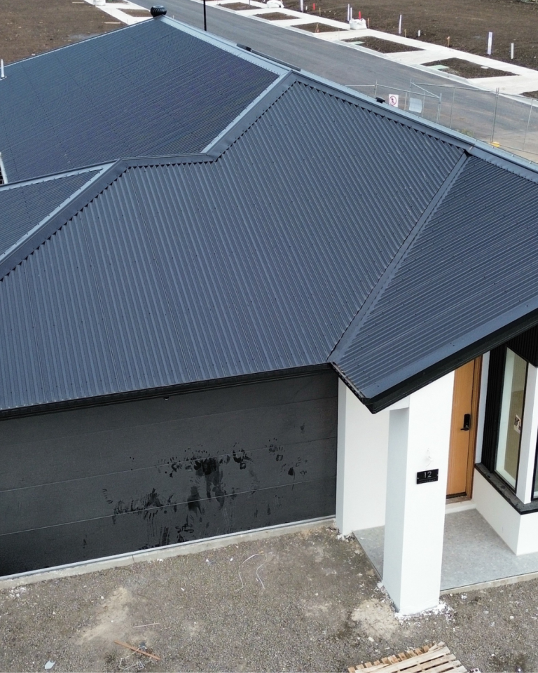 Detailed view of a Klip-Lok metal roofing installation above a garage on a new residential build by Pitch Perfect Roof Plumbing.