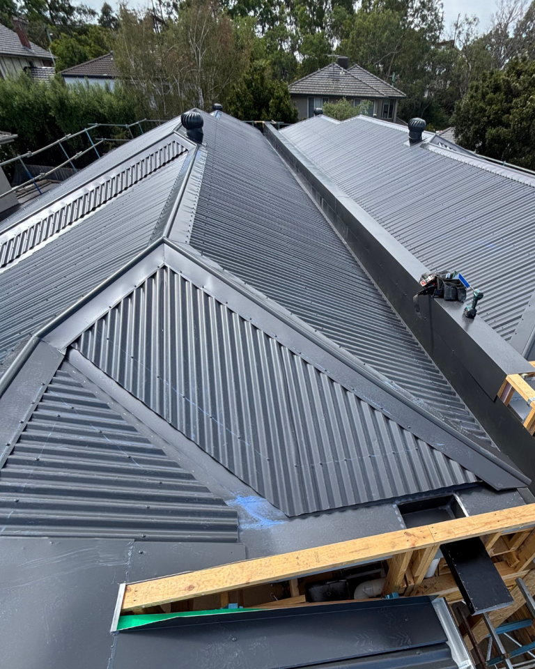 Aerial view of a new residential build with Klip-Lok metal roofing installed by Pitch Perfect Roof Plumbing during construction.