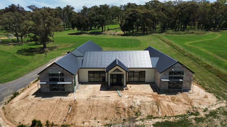 Aerial front view of a large new residential home featuring a dark metal roof installed by Pitch Perfect Roof Plumbing in Melbourne.