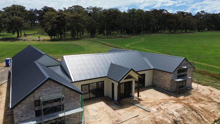 Aerial view of a new residential home featuring a dark metal roof installed by Pitch Perfect Roof Plumbing in Melbourne.